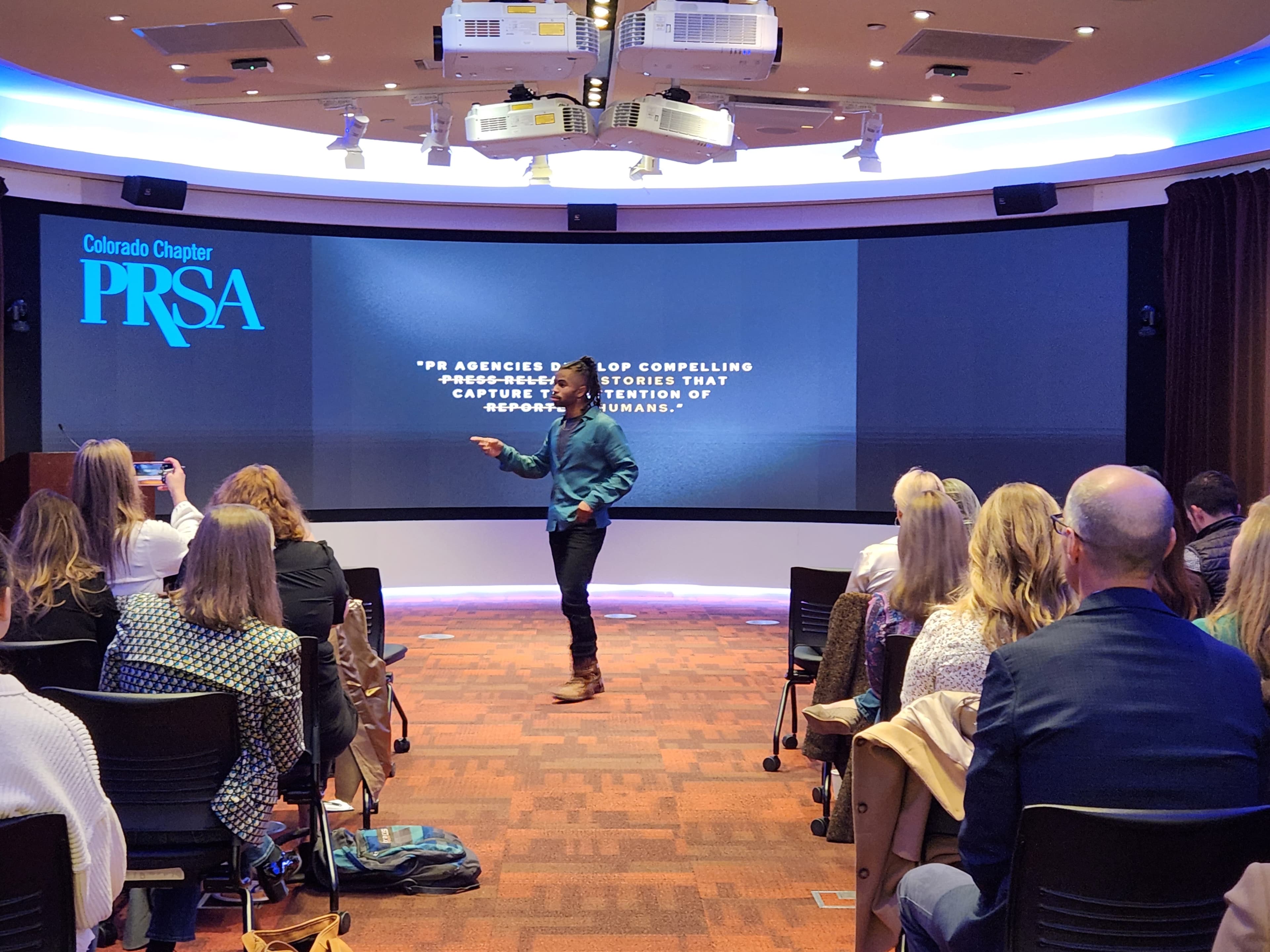 Imari Tuakli speaking on stage as a coach and facilitator